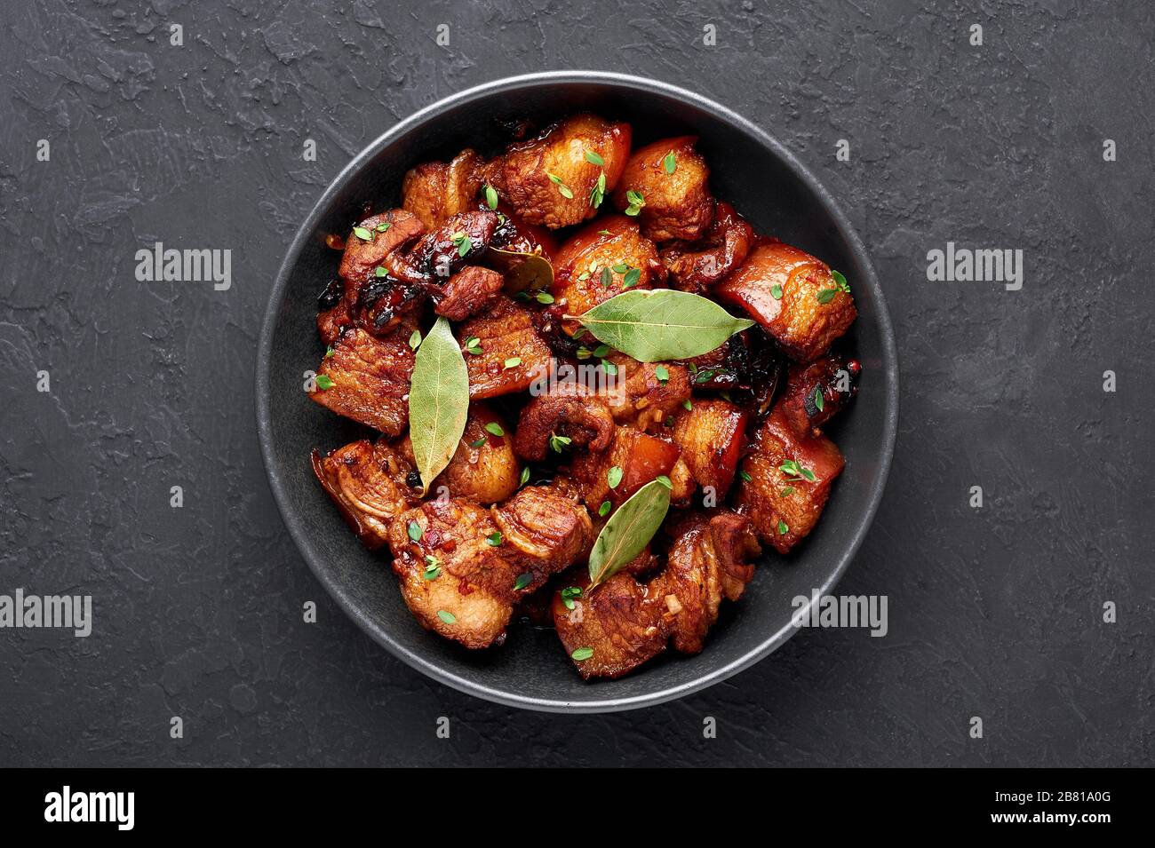Adobo Pork in black bowl at dark slate background. Pork Adobo or