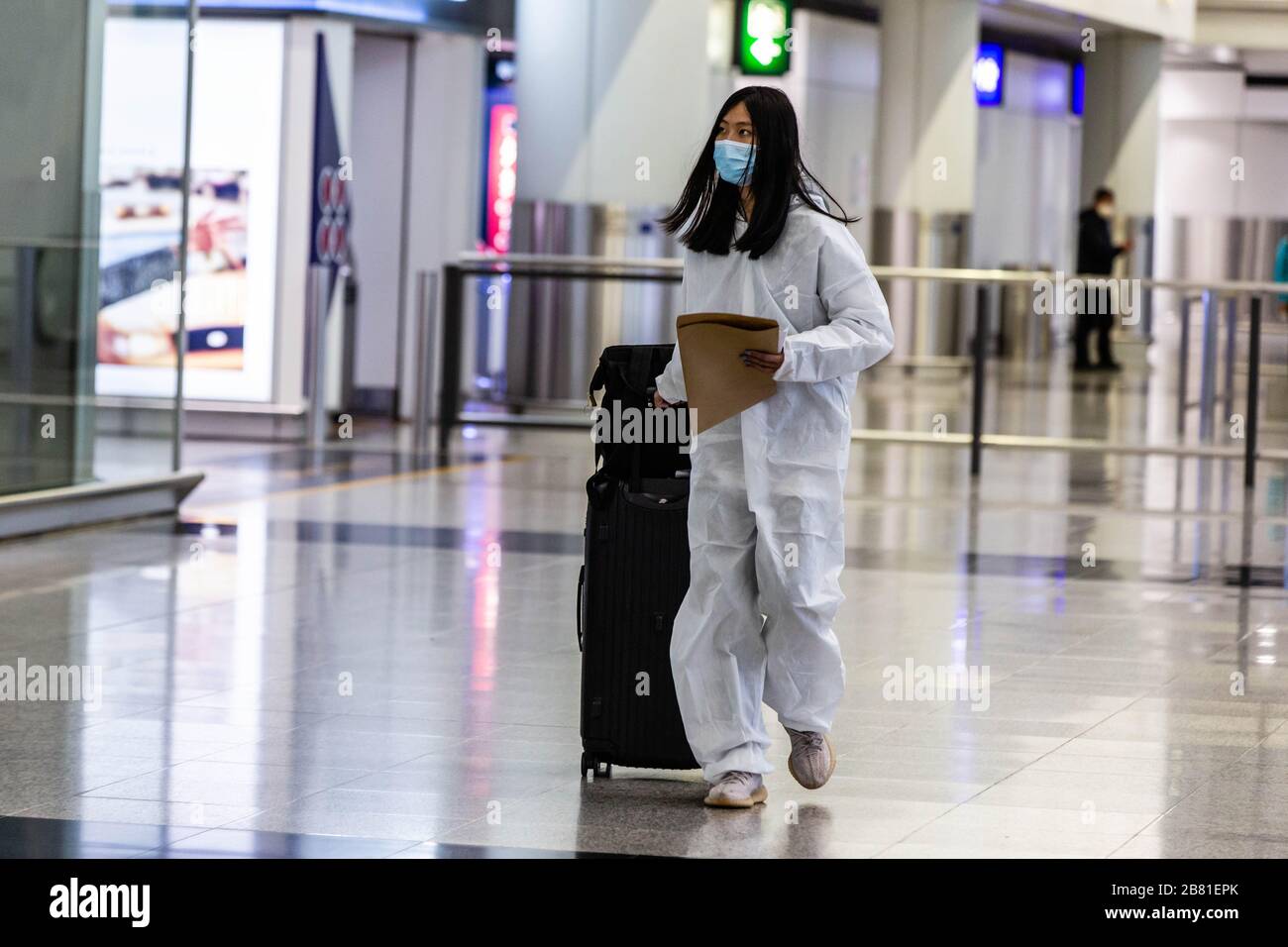 A masked passenger wearing a protective white robe as preventive measure  from catching the Covid-19 coronavirus. With the coronavirus outbreak  worsening around the world, hundreds of passengers and students fly back to