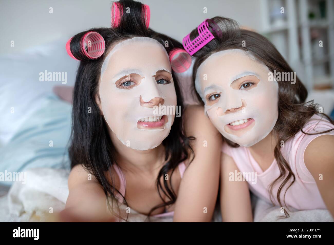 Mom and daughter feeling amused with facial mask on their faces Stock Photo