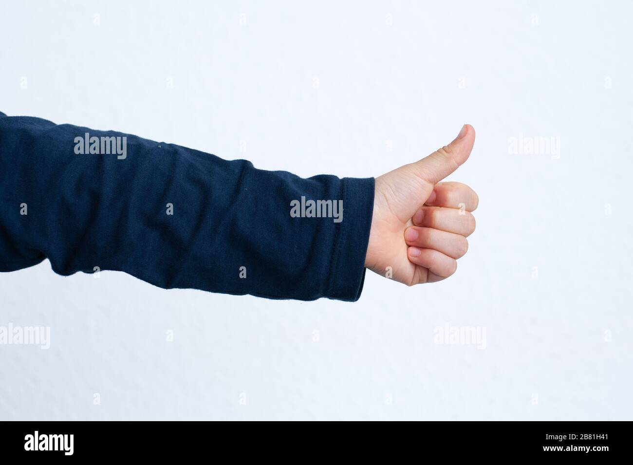 Childs hand with thumb up. Positive gesture of acceptation, ok, agreement, success etc.. Stock Photo
