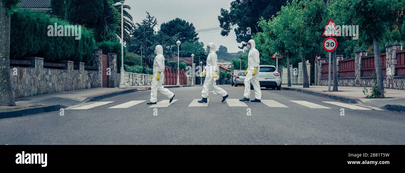 People in bacteriological protection suits walking down an empty street Stock Photo