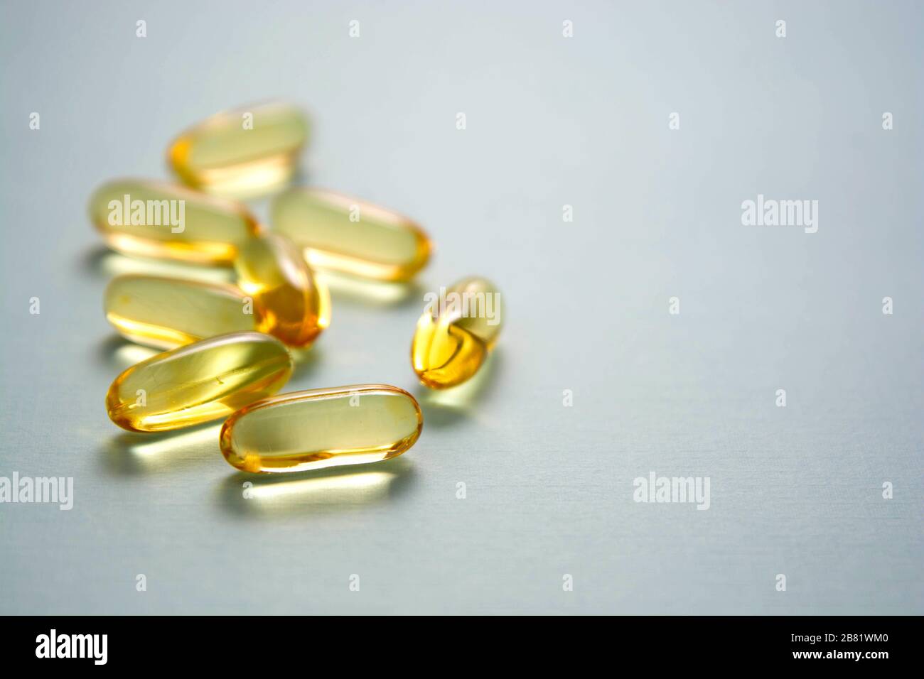 Omega3 fish fat oil capsules, isolated on blue background with copy