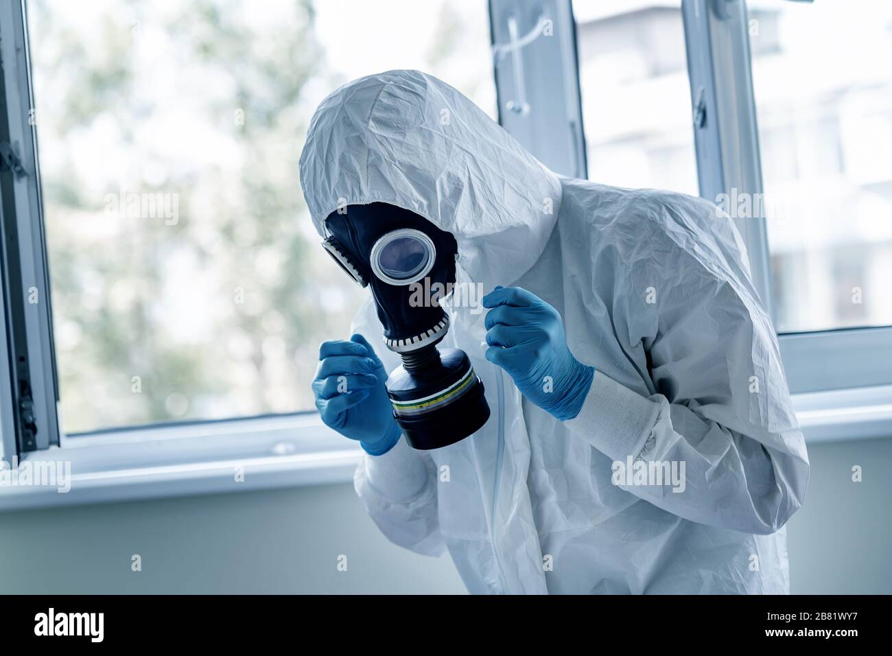 Man wearing protective biological suit and gas-mask due to mers coronavirus global pandemic warning and danger. Medic sphysician scientist make Stock Photo