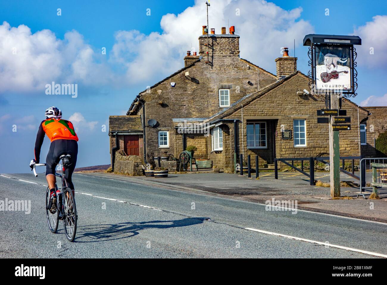 Man riding bike cycling past the Cat and Fiddle pub inn Cheshire the second-highest inn or public house in England, Stock Photo