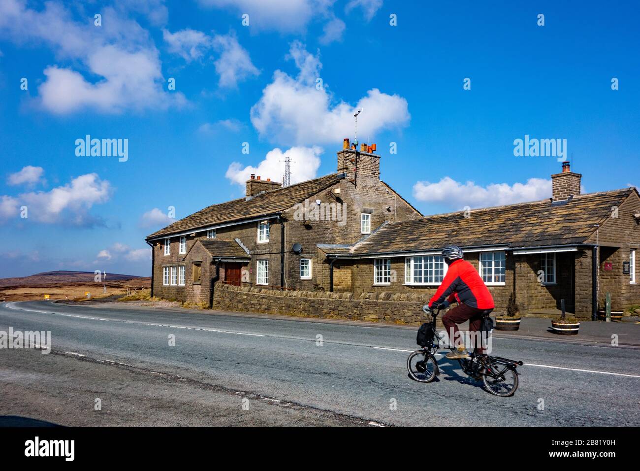 Man riding folding  bike cycling past the Cat and Fiddle pub inn Cheshire the second-highest inn or public house in England, Stock Photo
