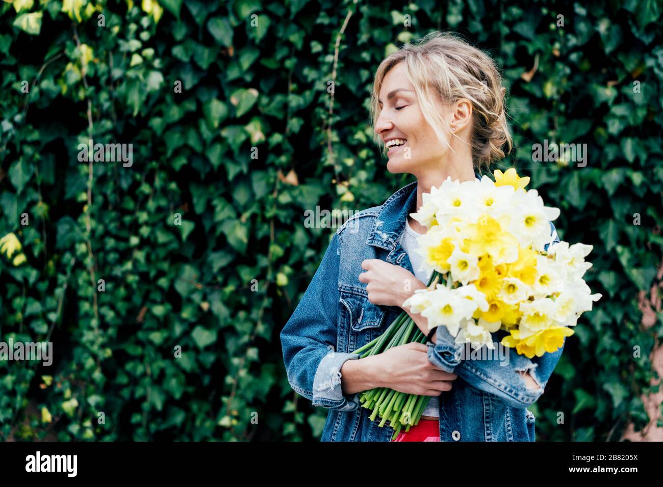 woman presses a bouquet of daffodils Stock Photo