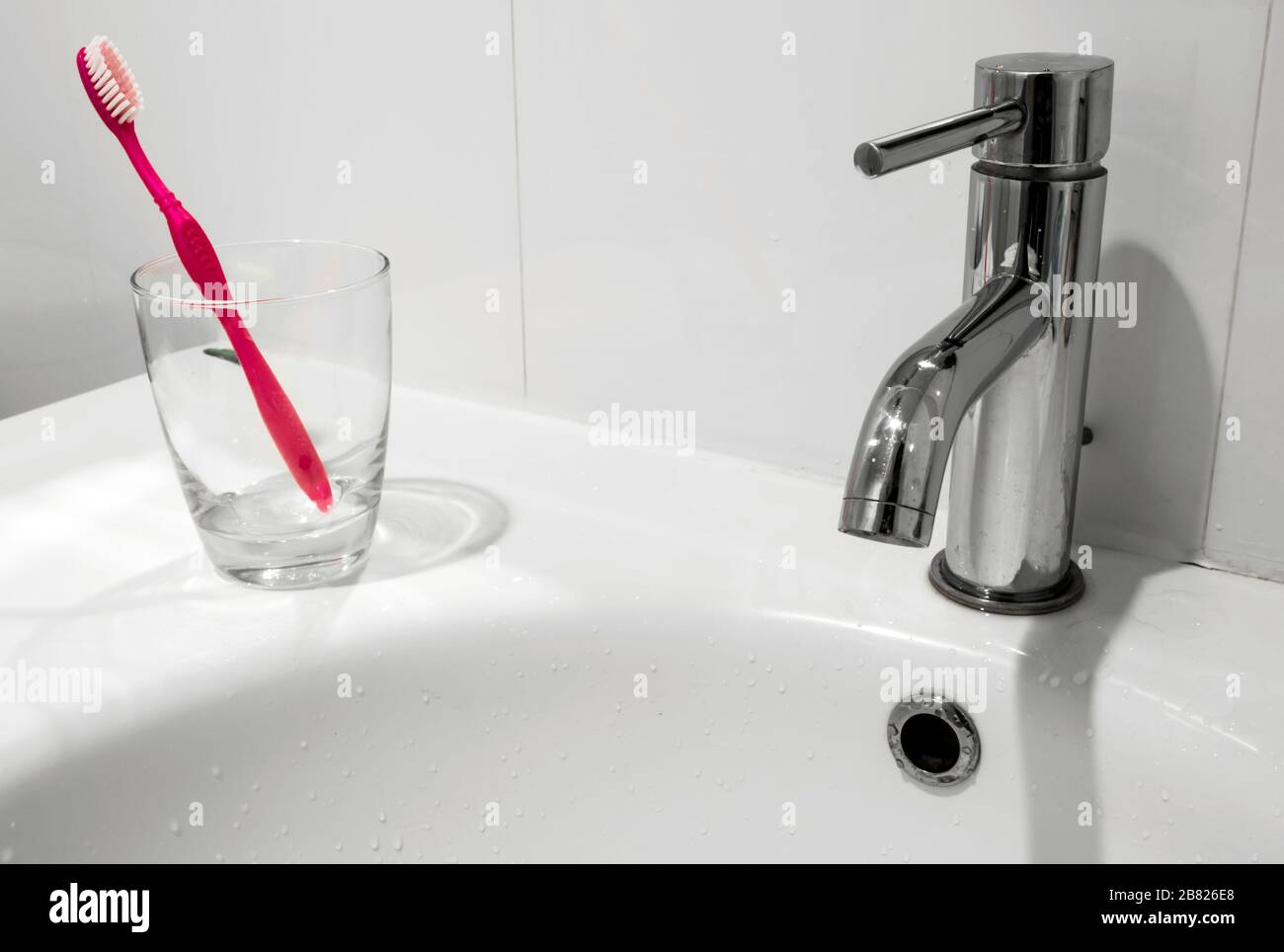 White bathroom faucet and wash basin with water glass and toothbrush Stock Photo