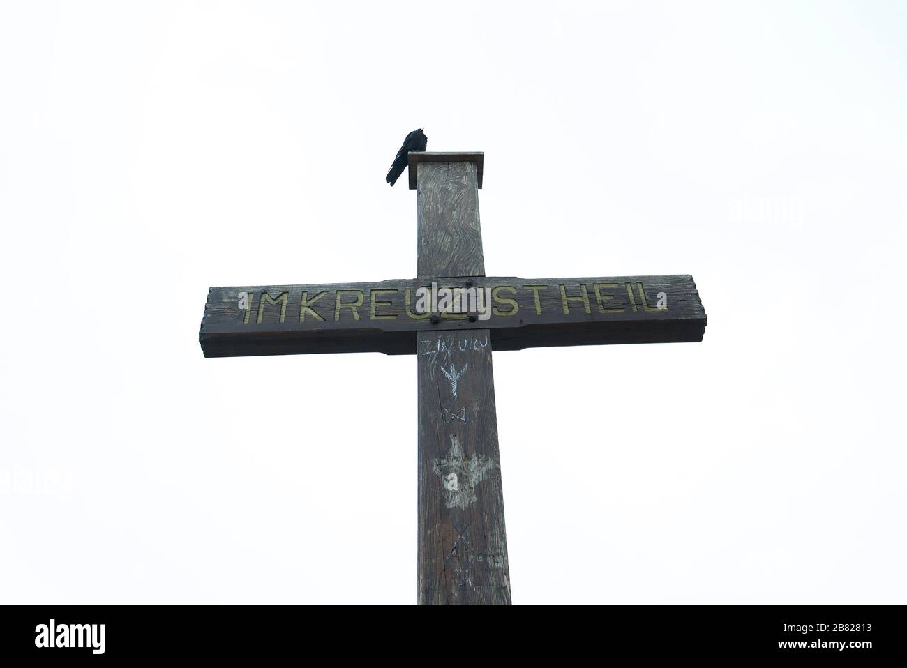 Crow sat on top of a cross. Untersberg, summit Salzburger Hochthron, summit cross, Flachgau, Salzburg, Austria. Berchtesgaden Alps. Im Kreuz ist Heil. Stock Photo