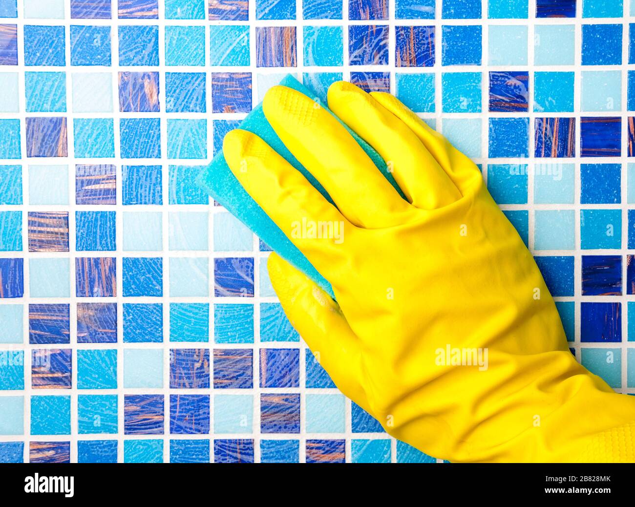 Person doing chores in bathroom at home cleaning wall with detergent