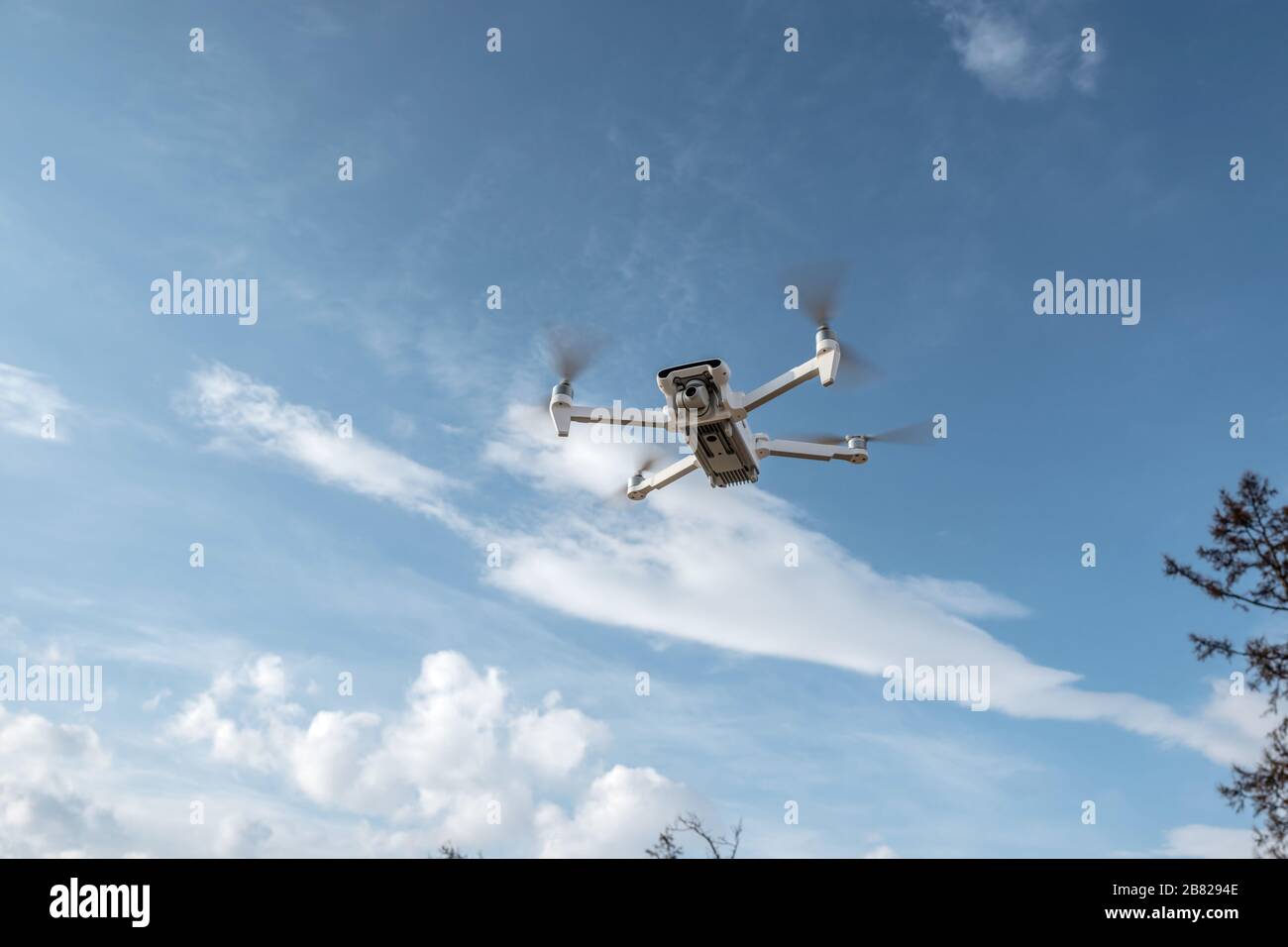 White quadrocopter drone with camera hangs in the air on the background of beautiful nature in winter. Shooting photos and videos from the air at alti Stock Photo