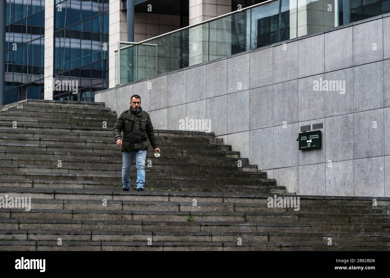 Brussels Business district, Brussels Capital Region / Belgium - 02 04 2020: Man walking down the front stairs of the Finance Tower Stock Photo