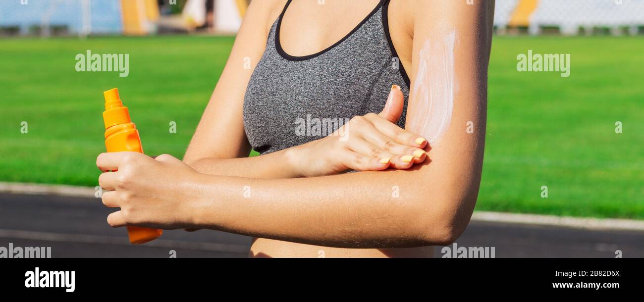 Young woman is applying sunscreen on her arms before physical