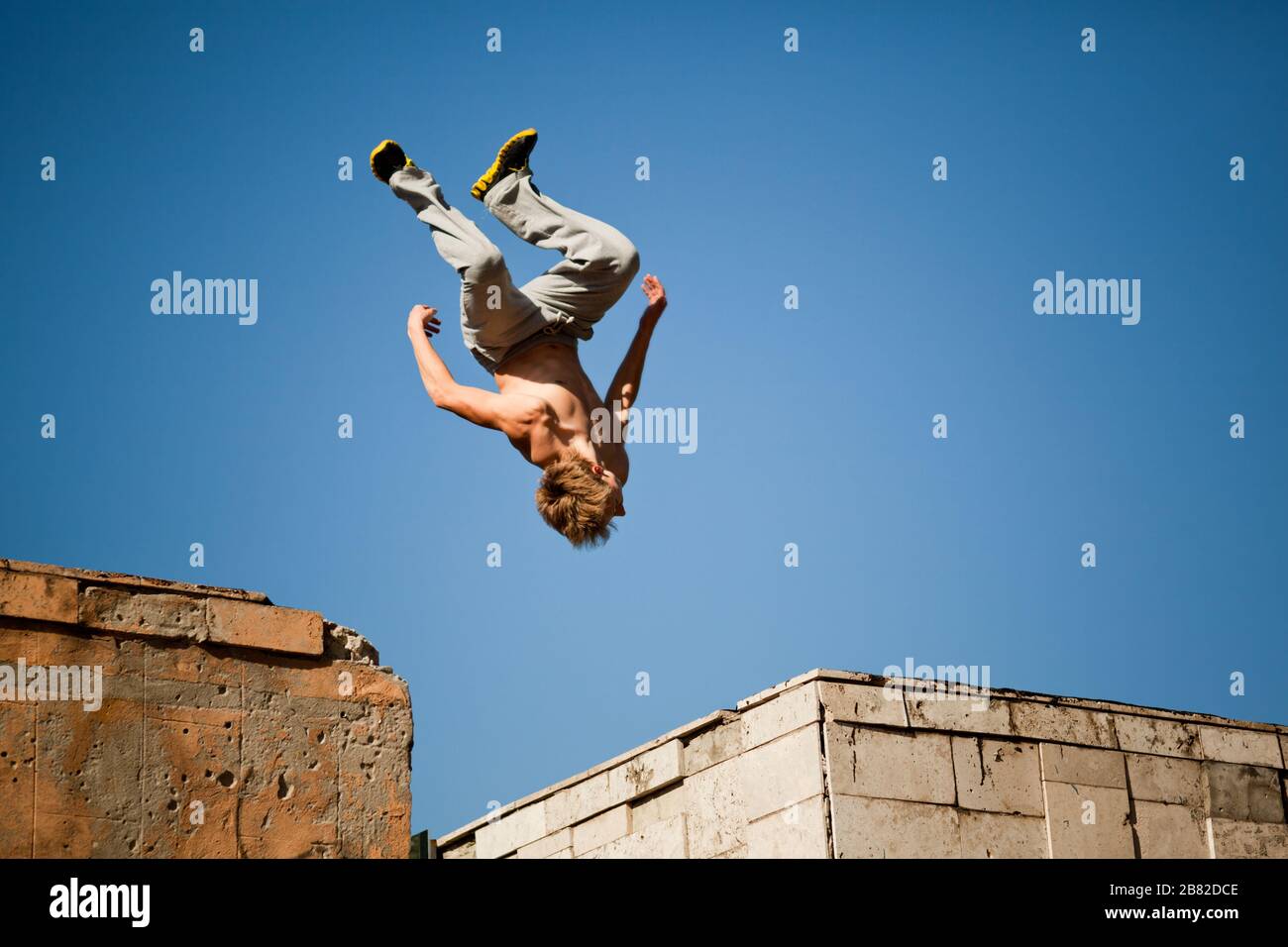 Young man jumping and practicing parkour between two buildings outside on  clear summer day with blue sky at background. Active lifestyle and extreme  s Stock Photo - Alamy