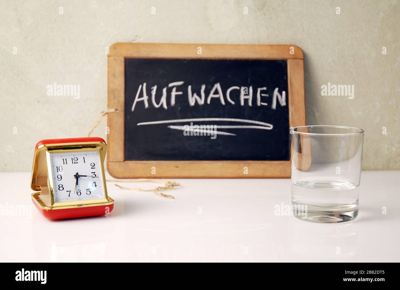 old timer with waterglas and a chalkboard witten in german Aufwachen, in english wake up Stock Photo