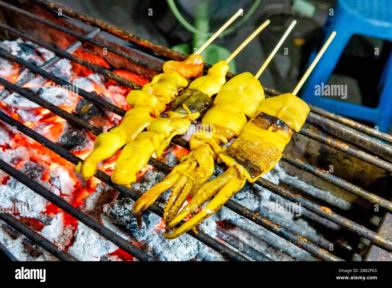 Plaa Mhuk Yang (Thai grilled squids) on a grill Stock Photo