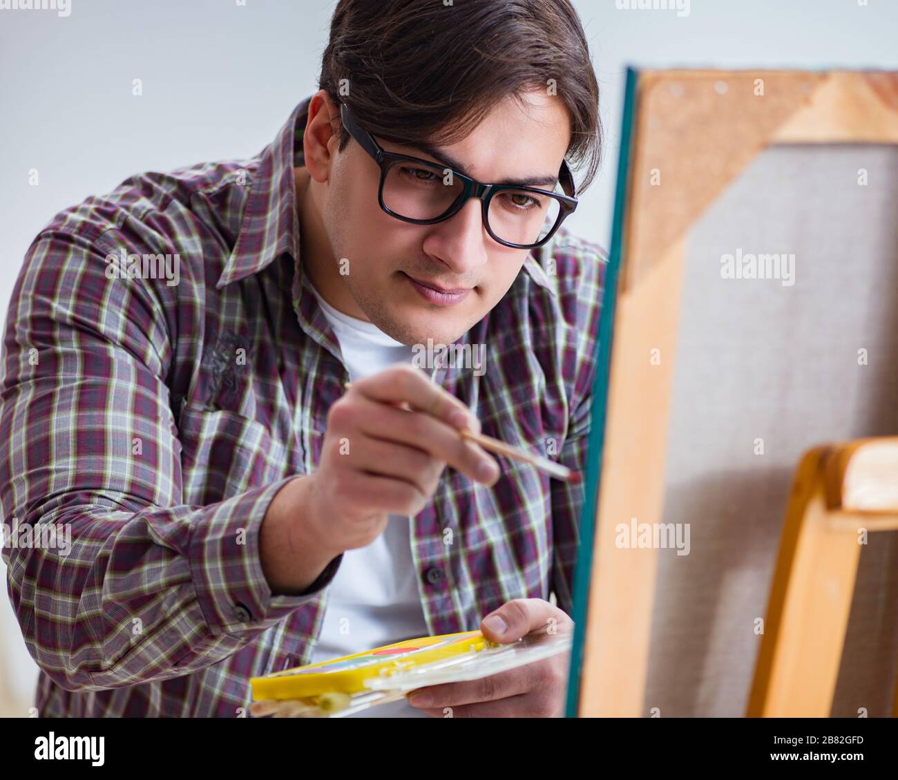 The young male artist drawing pictures in bright studio Stock Photo - Alamy