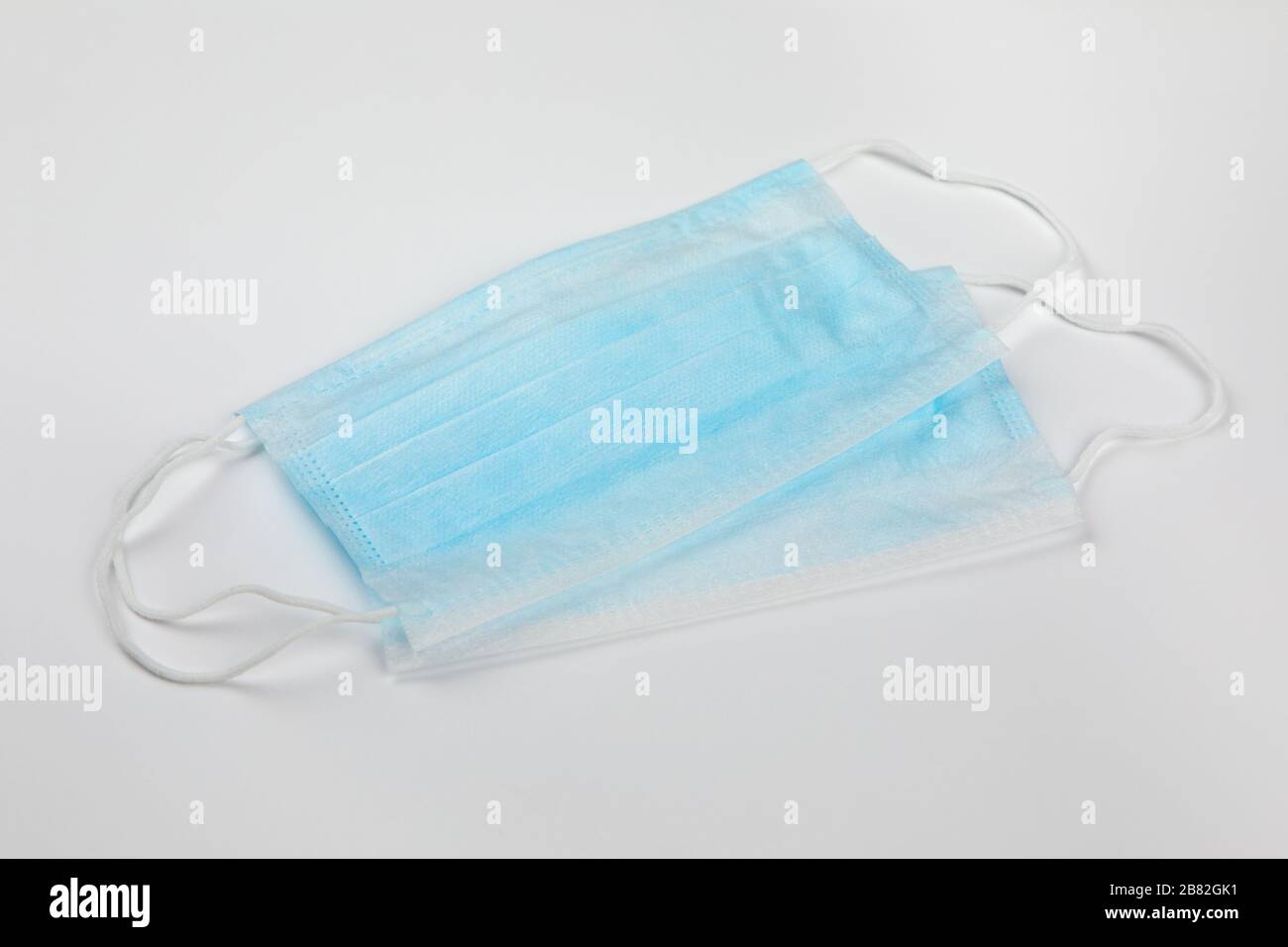 two blue surgical medical masks on white background Stock Photo - Alamy