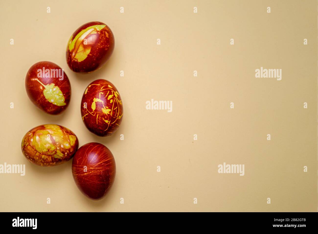 Chicken eggs colored with old-fashioned natural method by onion husks isolated on light brown. Topview of brown eggs with different natural patterns w Stock Photo