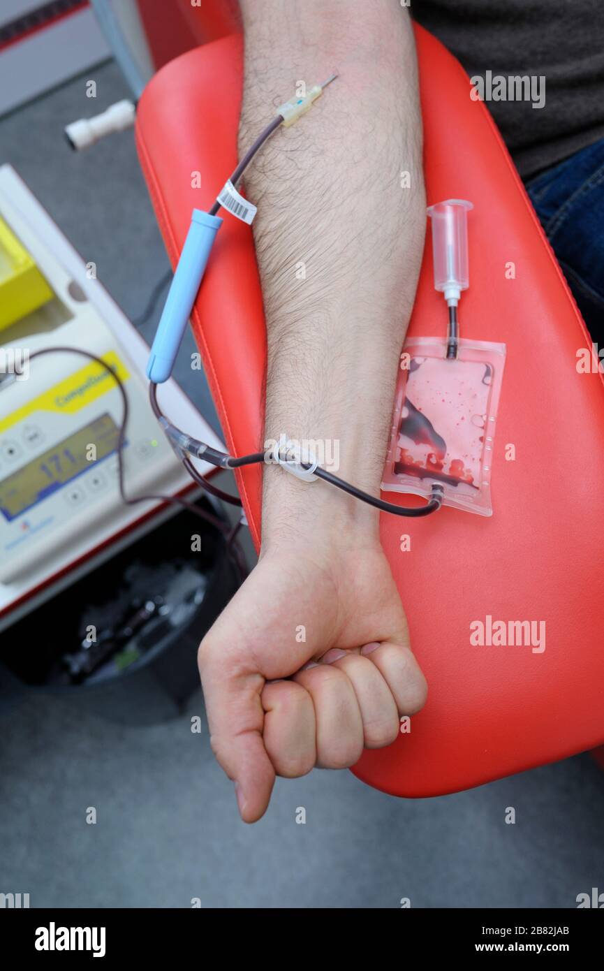 Arm on an armrest, hypodermic needle, tubes, container with blood