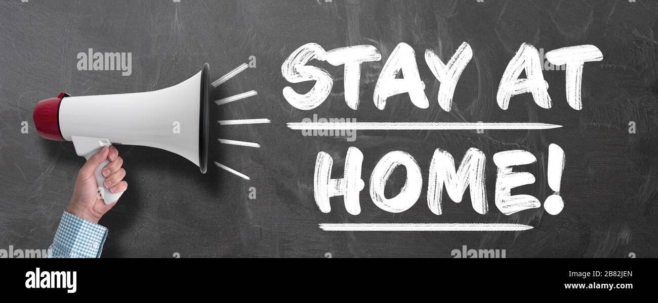 man with megaphone shouting STAY AT HOME, social distancing due to corona virus pandemic concept Stock Photo