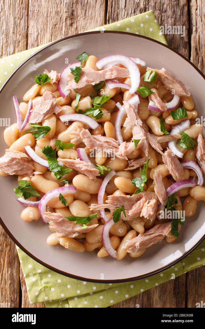 Tasty Mediterranean style tuna salad with white beans and onions close-up in a plate on the table. Vertical top view from above Stock Photo