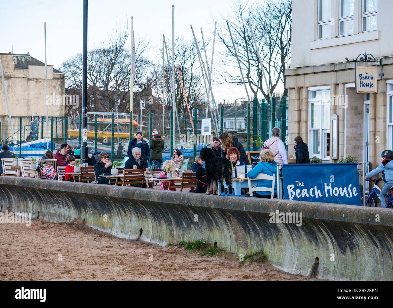 Portobello beach, Edinburgh, Scotland, United Kingdom. 19th March 2020. On a sunny Spring day, people are out enjoying the seaside. People sitting at the Beach House cafe pavement tables  during the Covid-19 Coronavirus pandemic Stock Photo