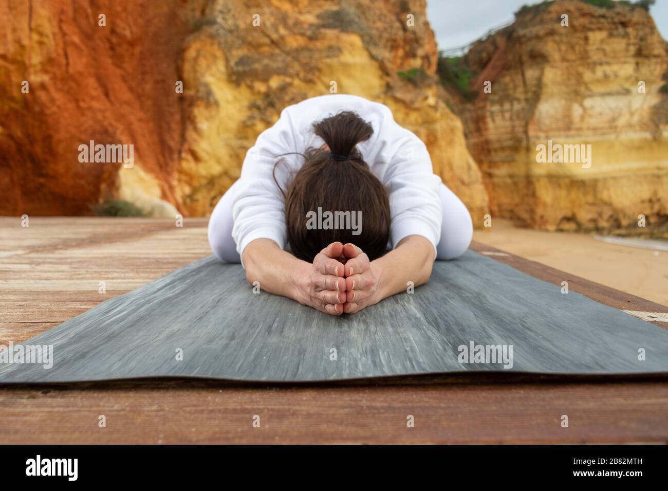 woman practicing yoga outside, child's pose. Stock Photo