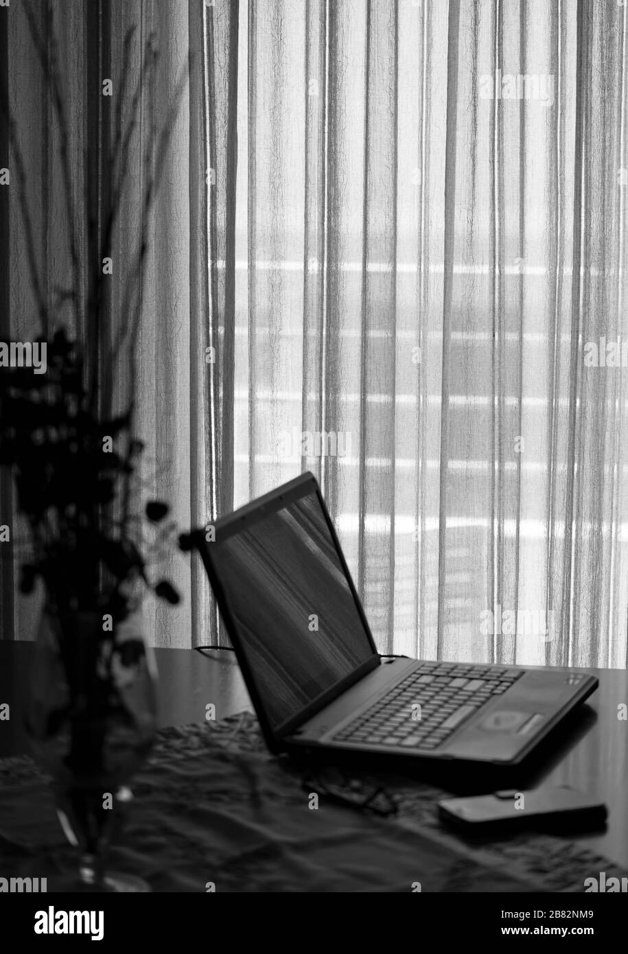 Laptop computer, mobile phone and glasses on a table in living room. Stock Photo