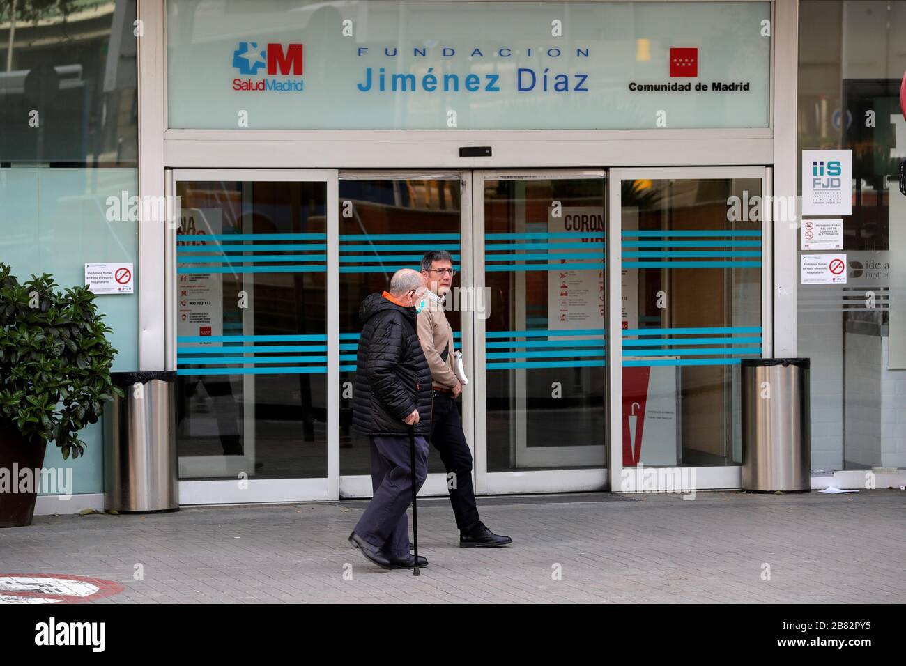 Madrid, Spain. 19th Mar, 2020. People walk outside the Jimenez Diaz Hospital in Madrid, Spain, 19 March 2020, where allegedly former Madrid Regional President Esperanza Aguirre and husband Fernando Ramirez have checked in for coronavirus. Credit: JUANJO MARTIN/EFE/Alamy Live News Stock Photo