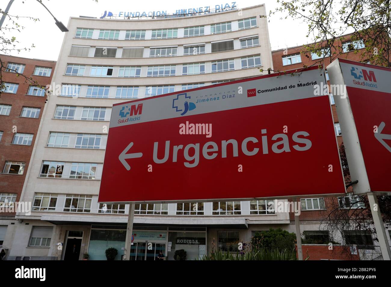 Madrid, Spain. 19th Mar, 2020. People walk outside the Jimenez Diaz Hospital in Madrid, Spain, 19 March 2020, where allegedly former Madrid Regional President Esperanza Aguirre and husband Fernando Ramirez have checked in for coronavirus. Credit: JUANJO MARTIN/EFE/Alamy Live News Stock Photo
