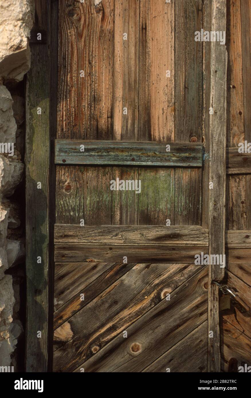 Beautiful, old, stained, wooden door set into a stone house in Lia (Lias), Epirus, Greece. The varnish is wearing, showing the grain, knots and texture in the wood. Stock Photo