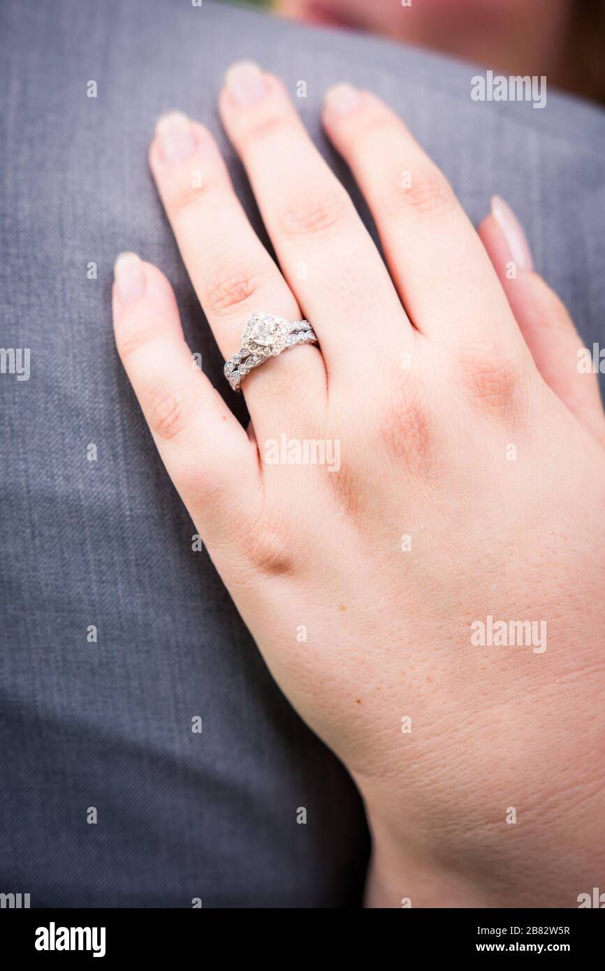 Bride displays diamond and white gold engagement ring and wedding band