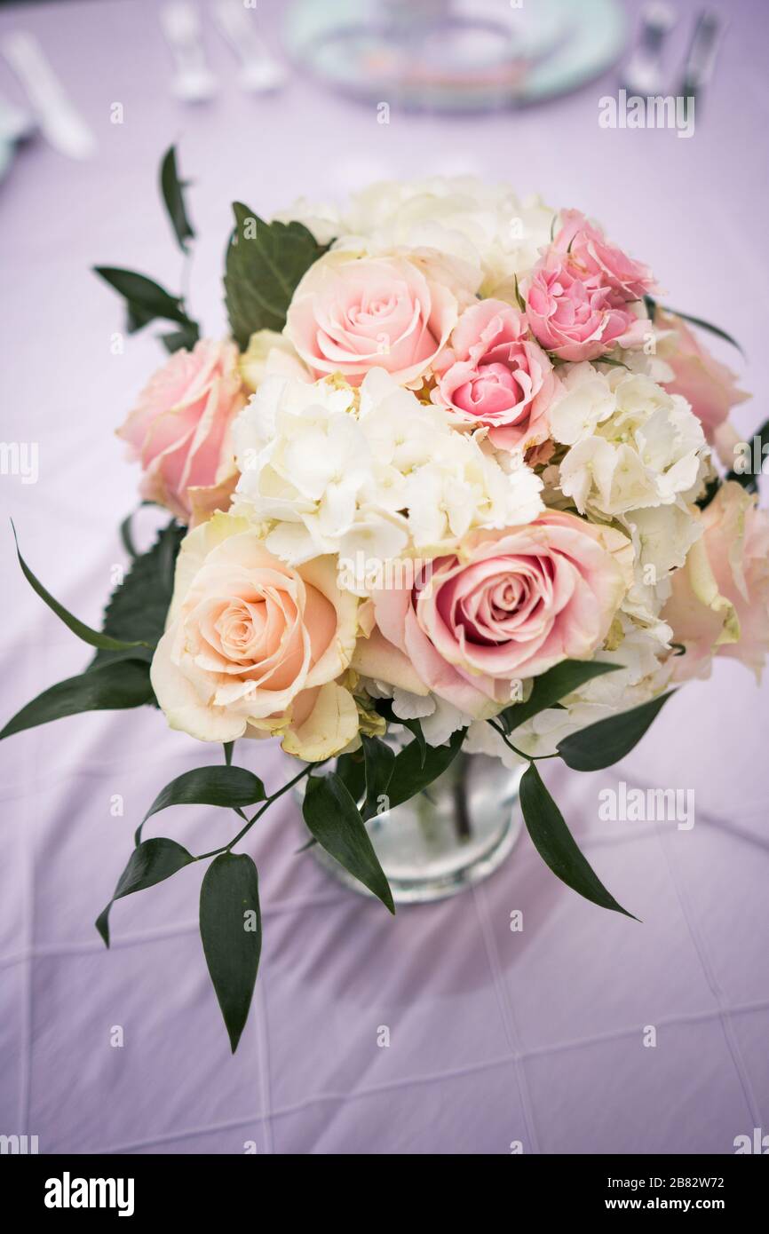 Floral bouquet of white, green and pink in vase on table at wedding reception Stock Photo