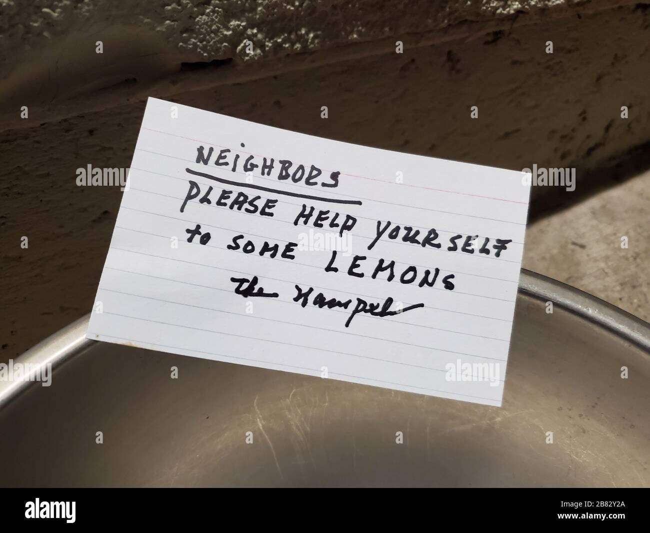 Close-up of a handwritten note placed on a bowl of lemons in a communal area of a neighborhood in San Ramon, California, with text reading 'Neighbors please help yourself to some lemons', a response to food shortages during an outbreak of COVID-19 coronavirus, March 13, 2020. () Stock Photo