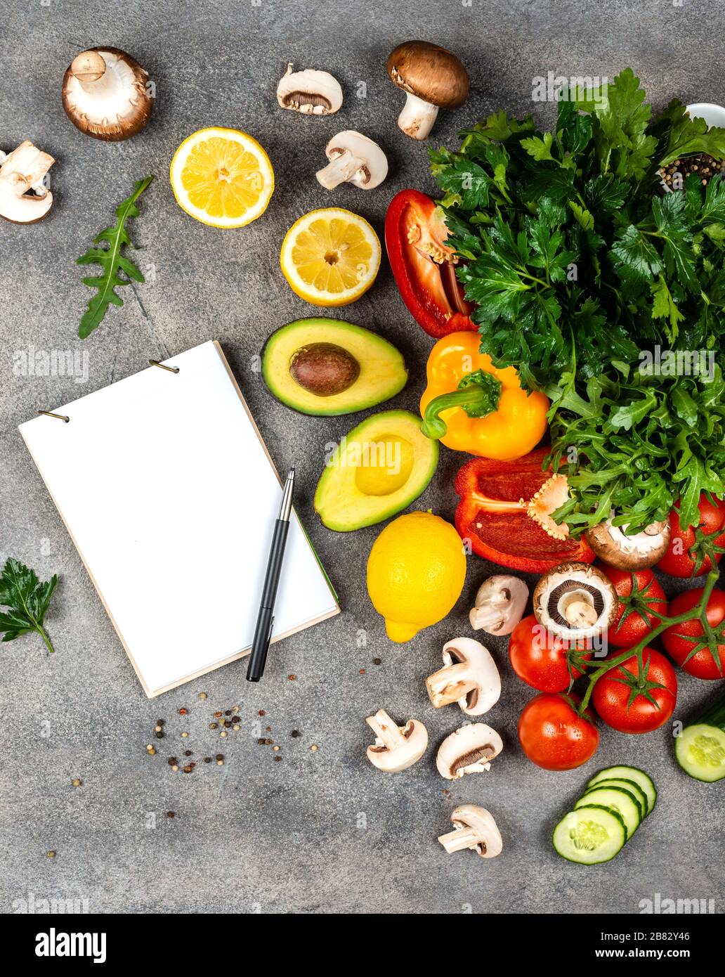 Different vegetables and ingredients for cooking vegeterian dishes. A book for writing recipes lies on a table. Copy space for text Stock Photo
