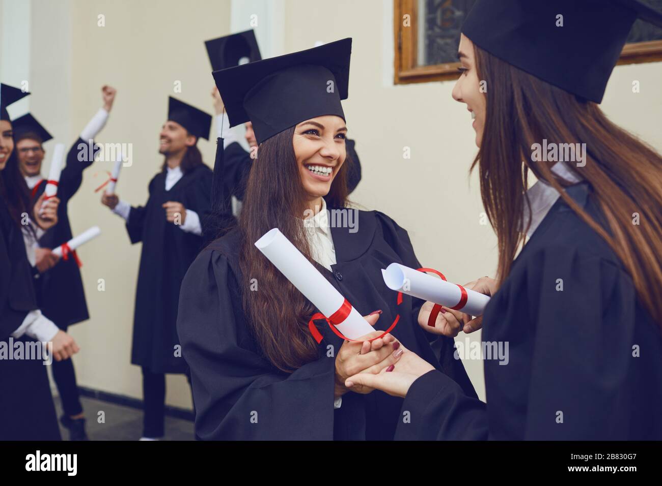 Female graduates with diplomas hugging laugh Stock Photo - Alamy