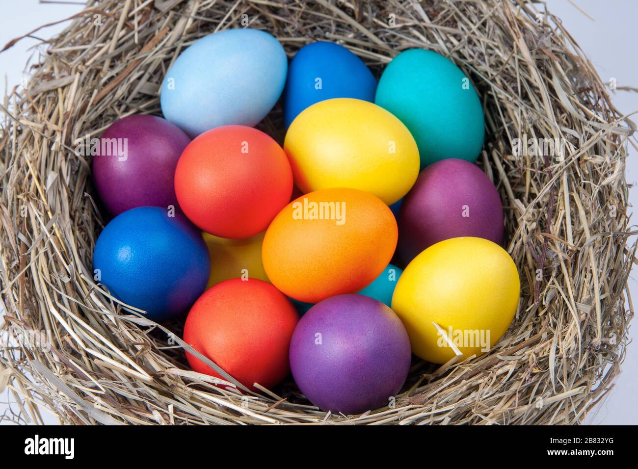 Multicolored eggs in nest in the hay. Concept easter. Stock Photo