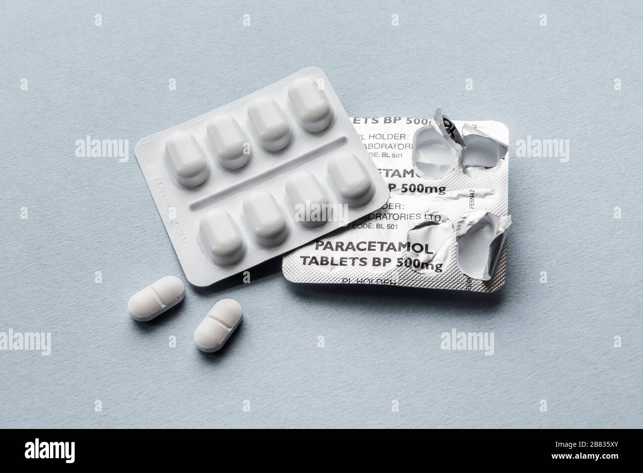 Paracetamol tablets in a blister pack, two tablets removed, against a plain background Stock Photo