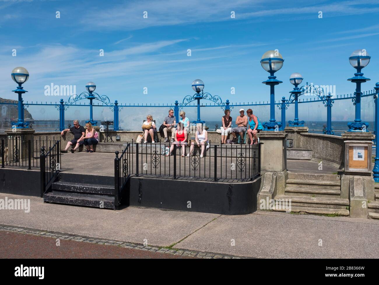 People relaxing in sunshine on the bandstand on the promenade at Llandudno, Conwy, Wales, Uk Stock Photo