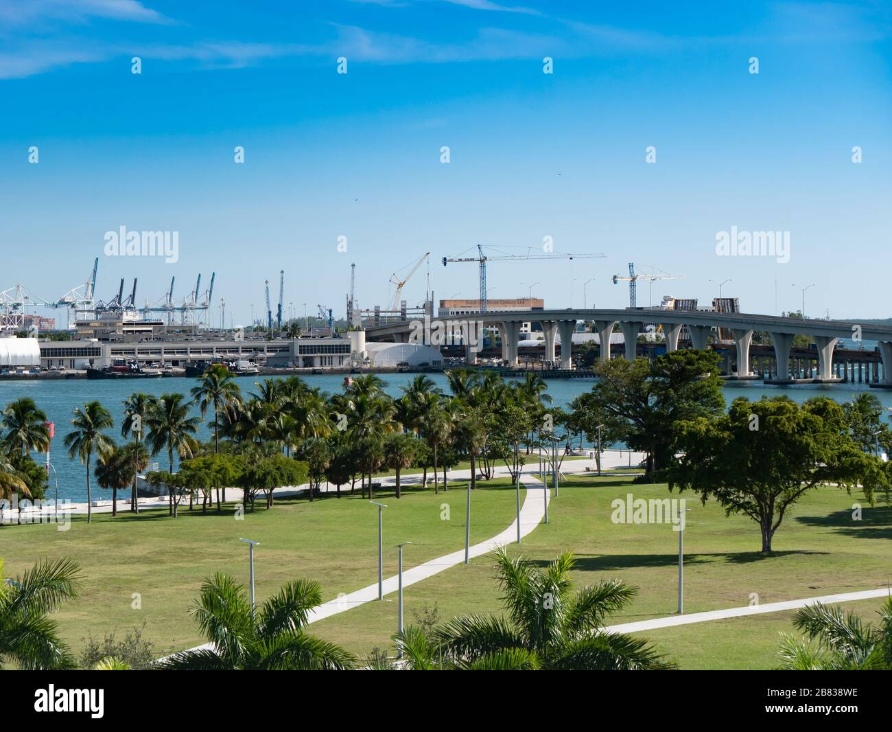 Port of Miami water front park, bridge overpass, and cranes for loading ships Stock Photo