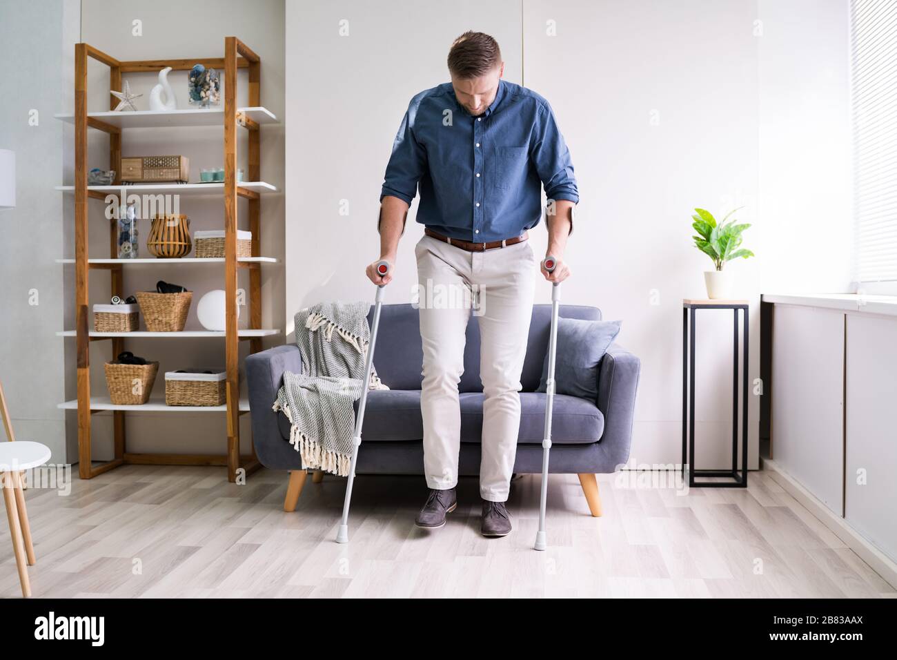 Disabled Young Man Using Crutches To Walk Stock Photo