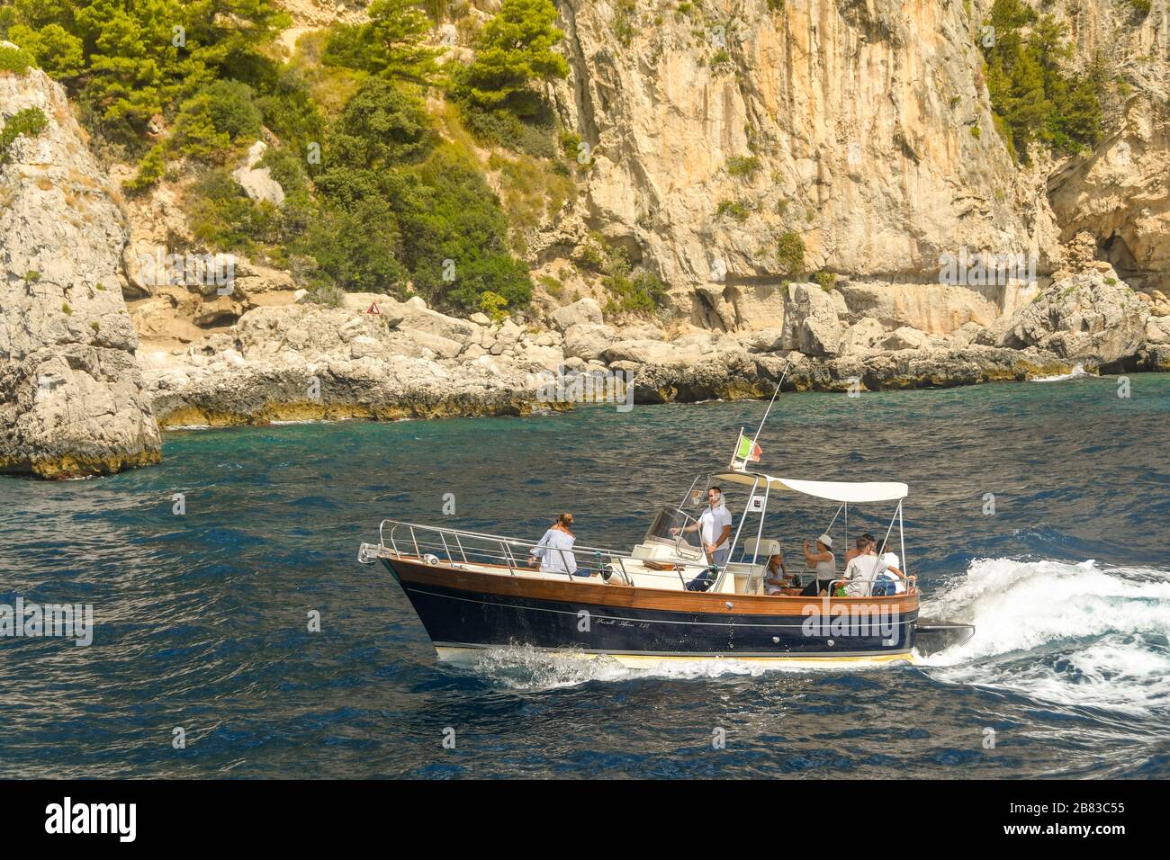 ISLE OF CAPRI, ITALY - AUGUST 2019: People on board a small motor boat on a trip around the Isle of Capri. Stock Photo