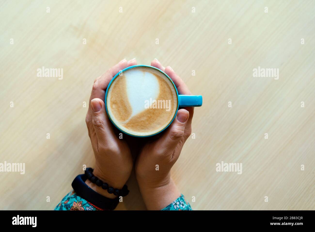 Female hands hugging a large mug with cappuccino.  Stock Photo