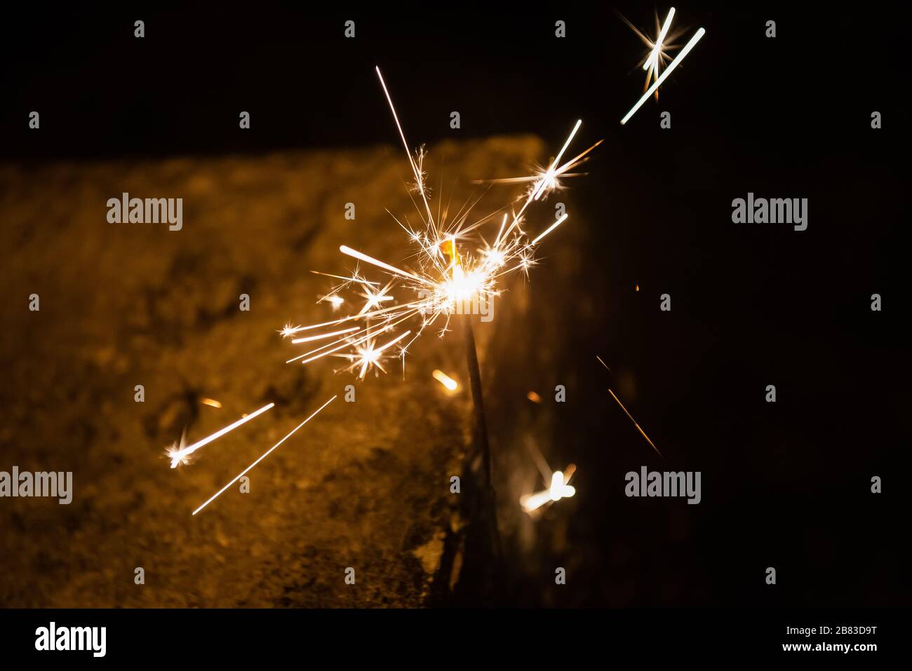 Burning sparking stick starlight fireworks pyrotechnic dark black warm background Stock Photo