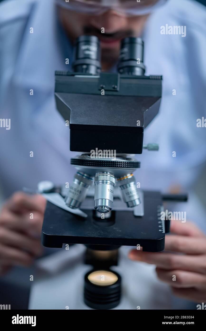 Young scientist looking through a microscope in a laboratory. Young scientist doing some research. Stock Photo