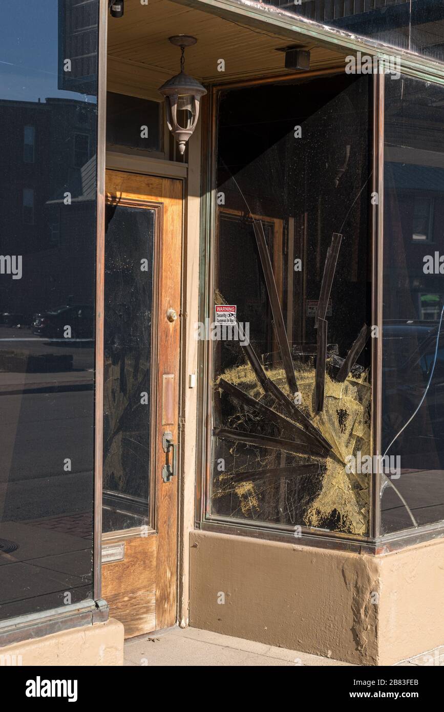 Cracked glass window pane by shop door looking like rioters have tried to enter the store Stock Photo