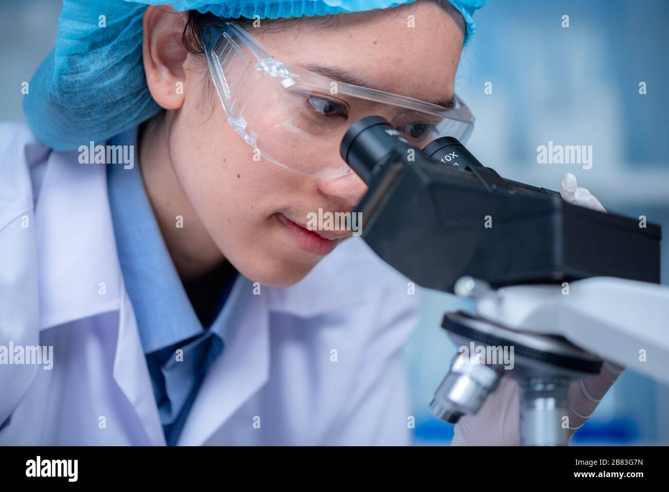 Young scientist looking through a microscope in a laboratory. Young scientist doing some research. Stock Photo
