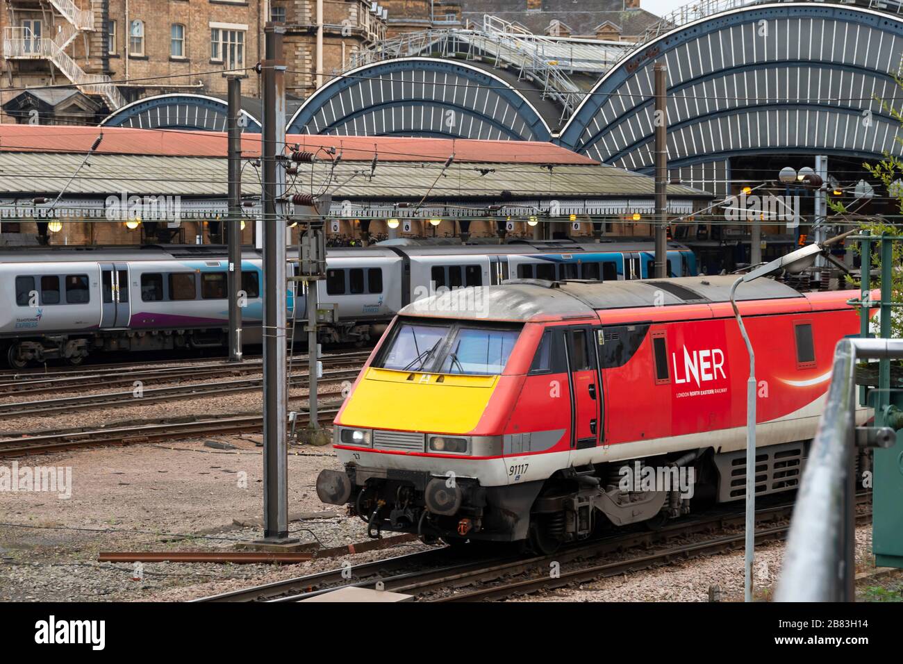 London North Eastern Railway electric train on the East Coast Main Line at York Railway Station, Yorkshire, England. Trans Pennine Express behind. Stock Photo