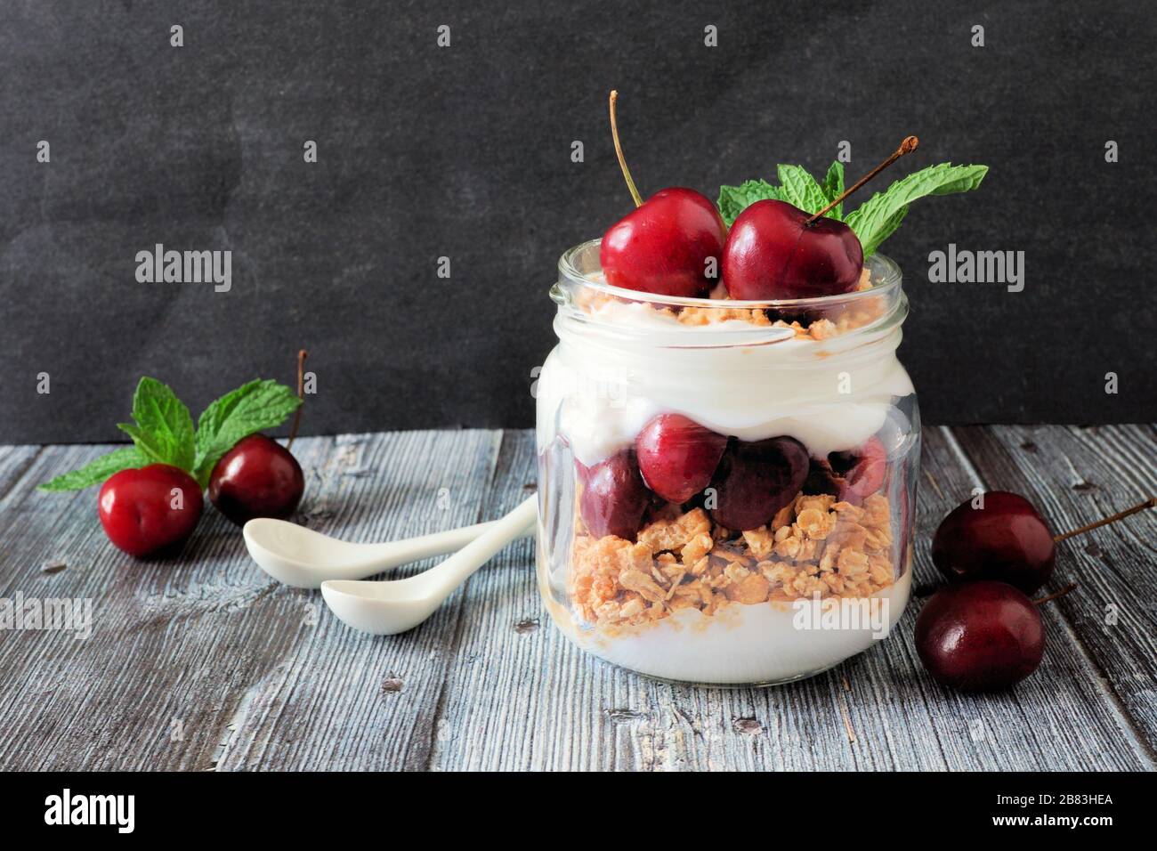 Delicious cherry parfait in a mason jar, scene on dark rustic background Stock Photo