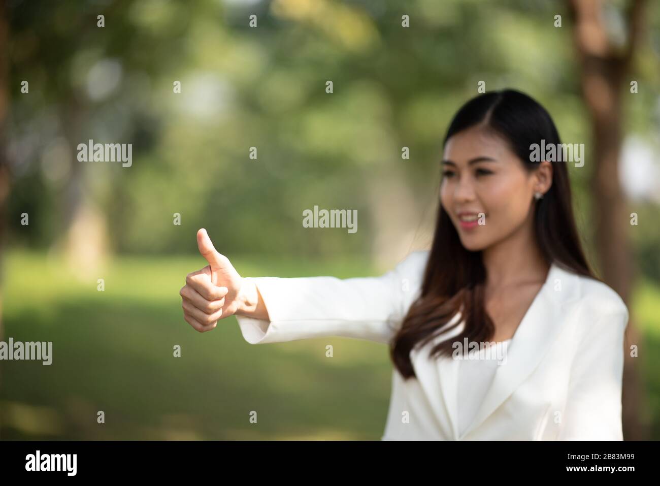 successful girl pointing thumb up; portrait of cheerful smiling woman ...